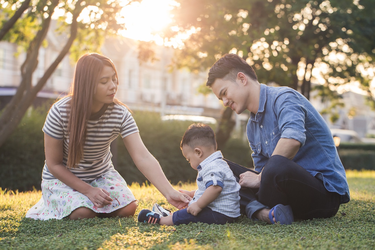 A young asian family sitting on the grass playing with their young son