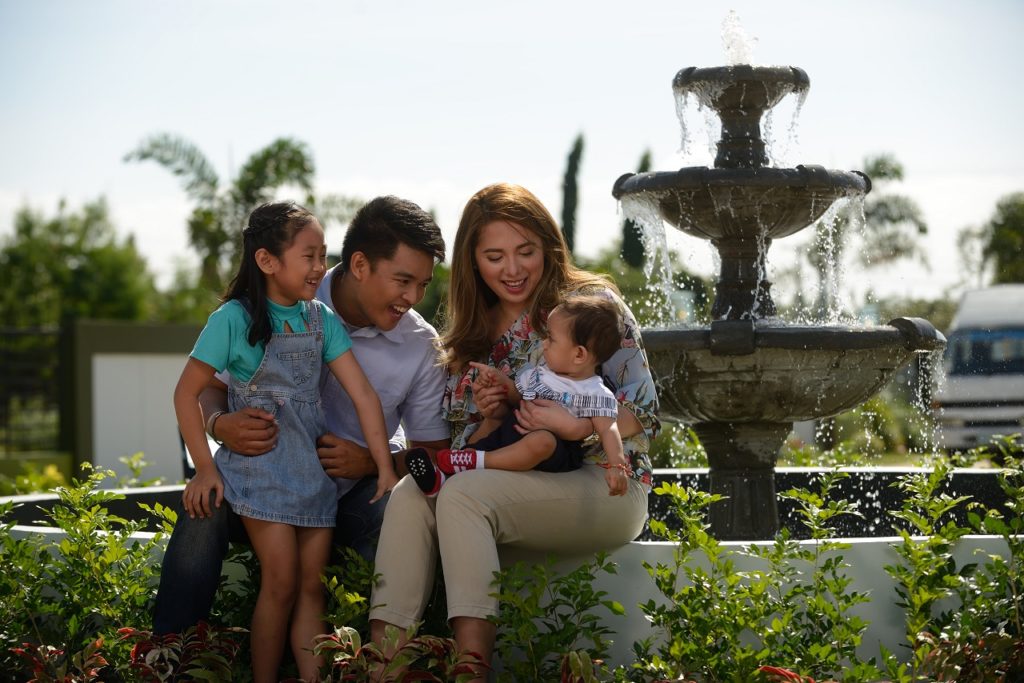 Family sitting on a fountain made by the best housing developer in the philippines